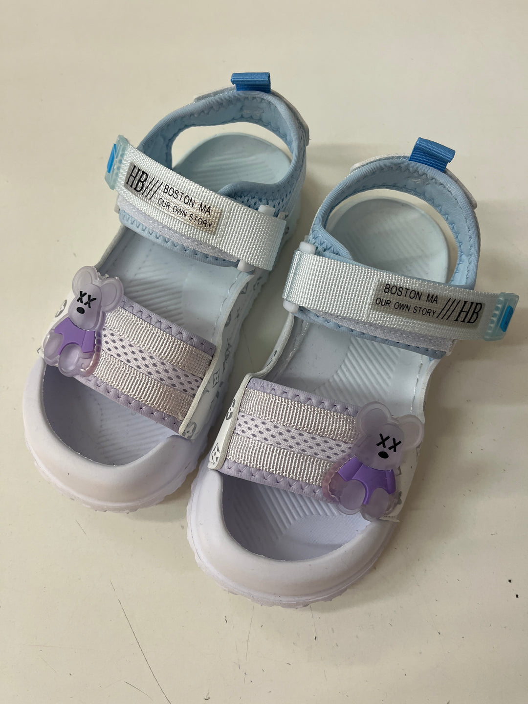 Pair of children's sandals with floral decorations on a light background