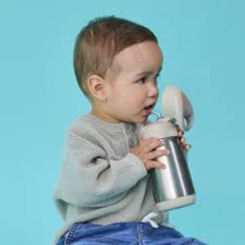 Child holding a silver tumbler with a blue background