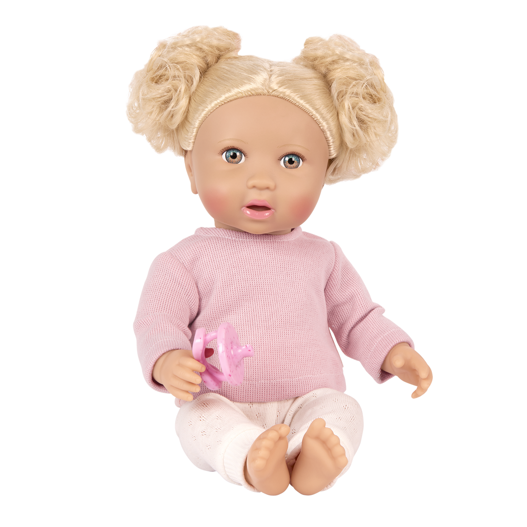 Doll with blonde hair styled in pigtails, wearing a pink sweater and holding a pink dummy toy on a white background.
