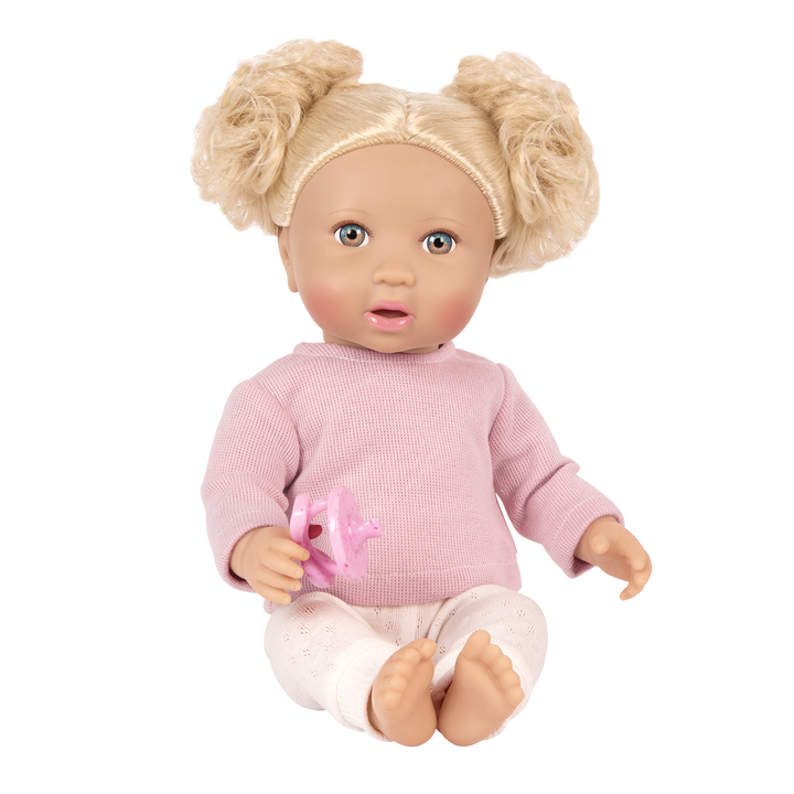 Doll with blonde hair styled in pigtails, wearing a pink sweater and holding a pink dummy toy on a white background.