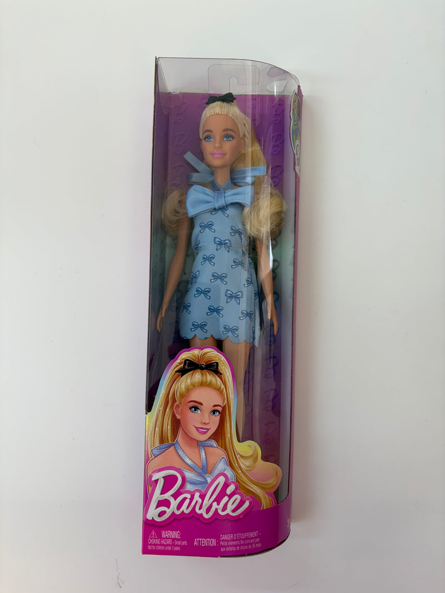 Barbie doll in a blue dress with blonde hair in a clear packaging box on a white background