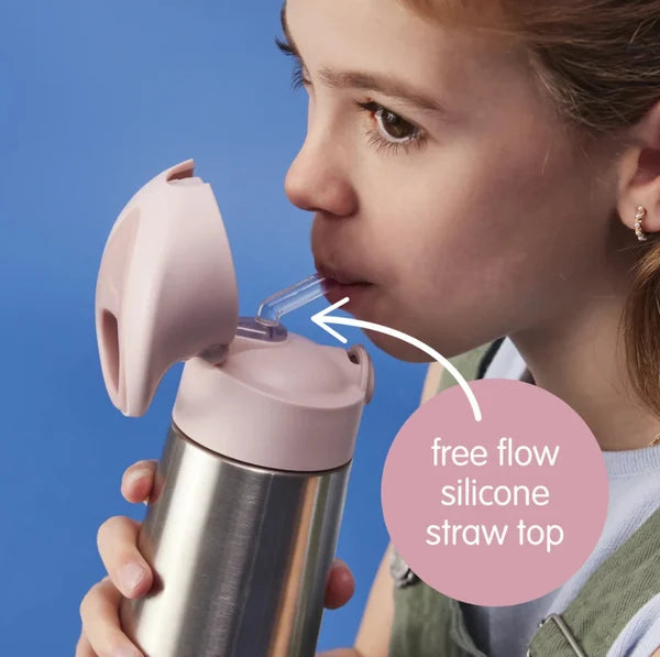 A close-up of a child drinking from a stainless steel water bottle with a pink flip-top straw lid. The child is shown in profile against a solid blue background, with a text bubble reading 'free flow silicone straw top' pointing to the straw connection.