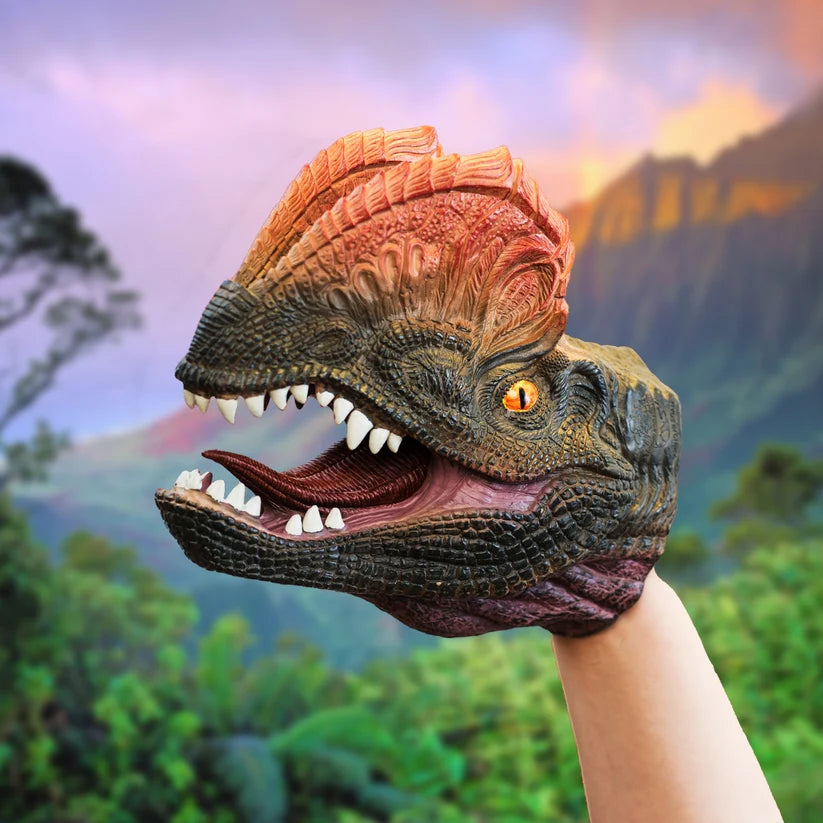 A dinosaur dinosaur head hand puppet being worn on a person's hand, set against a blurred background of a prehistoric landscape.