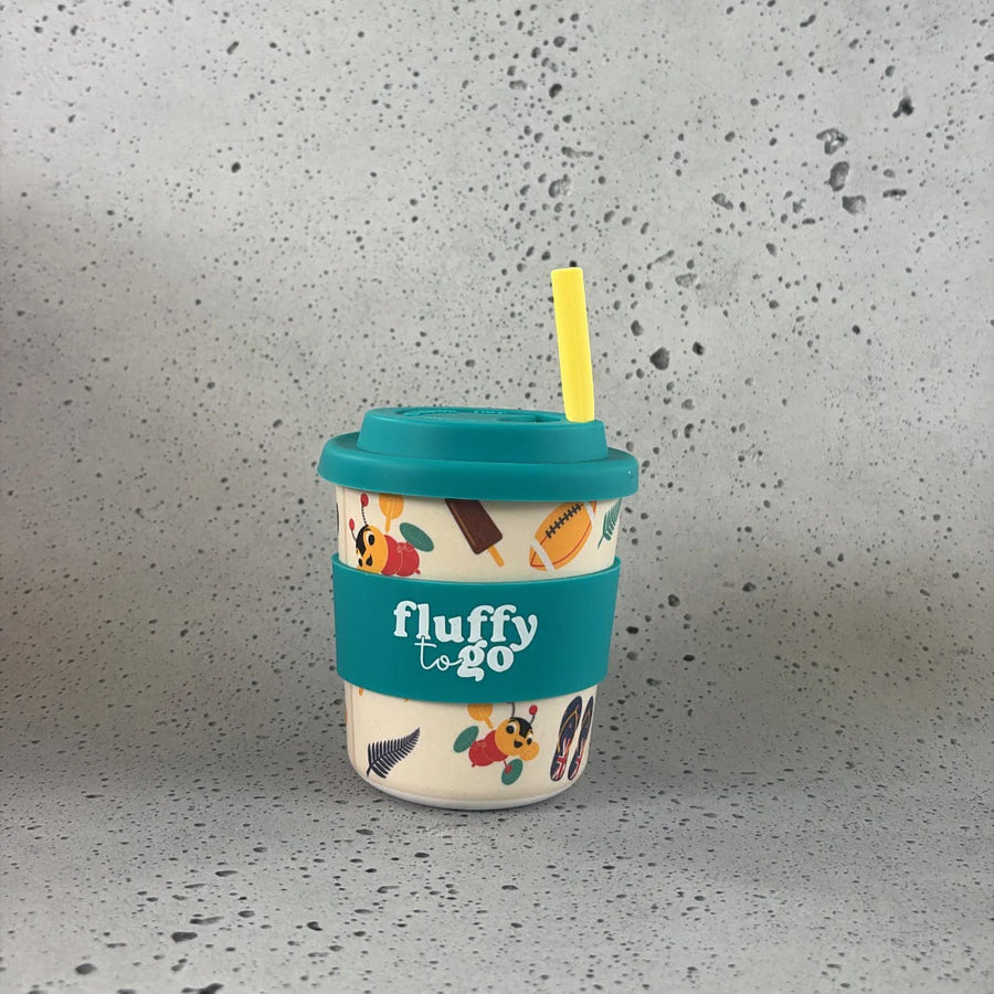 Reusable cup with colorful Kiwiana design and teal lid on a gray surface
