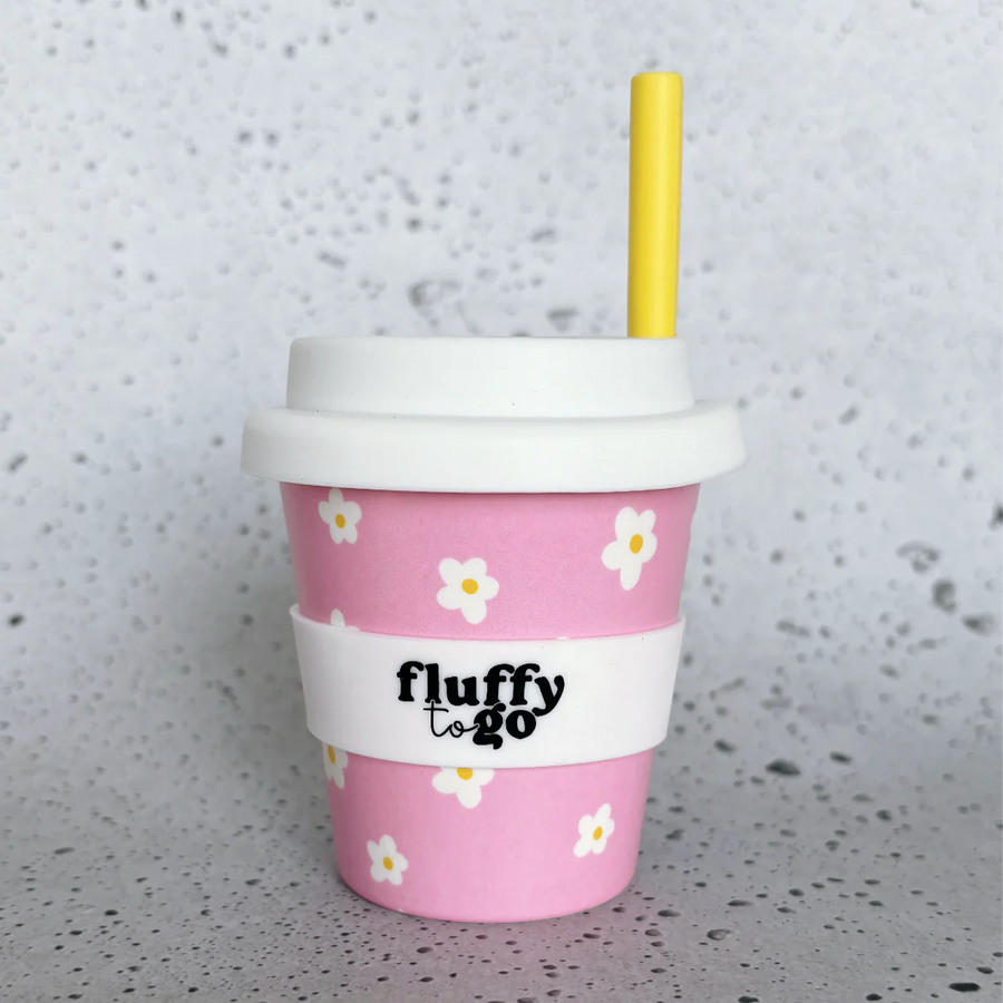 Pink fluffy to go cup 235ml with floral daisy design and white lid on a speckled gray surface