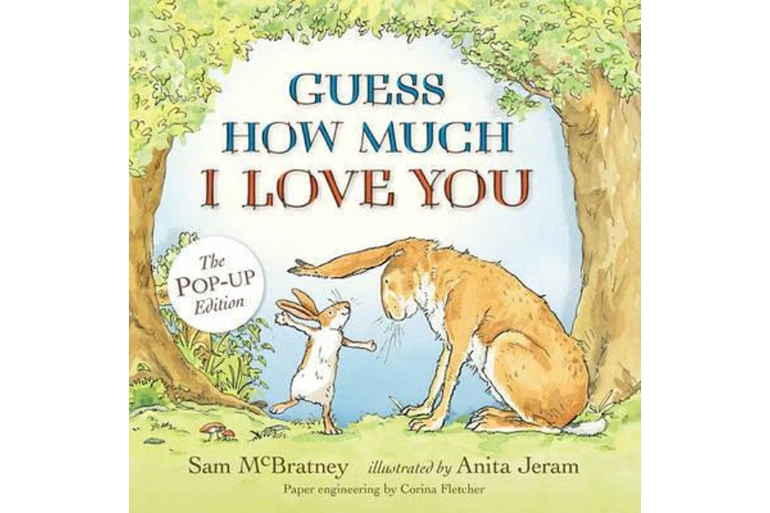 Front cover of the children's book 'Guess How Much I Love You' Pop-Up Edition, featuring a whimsical illustration of a rabbit and a hare under a tree with blue and brown lettering.