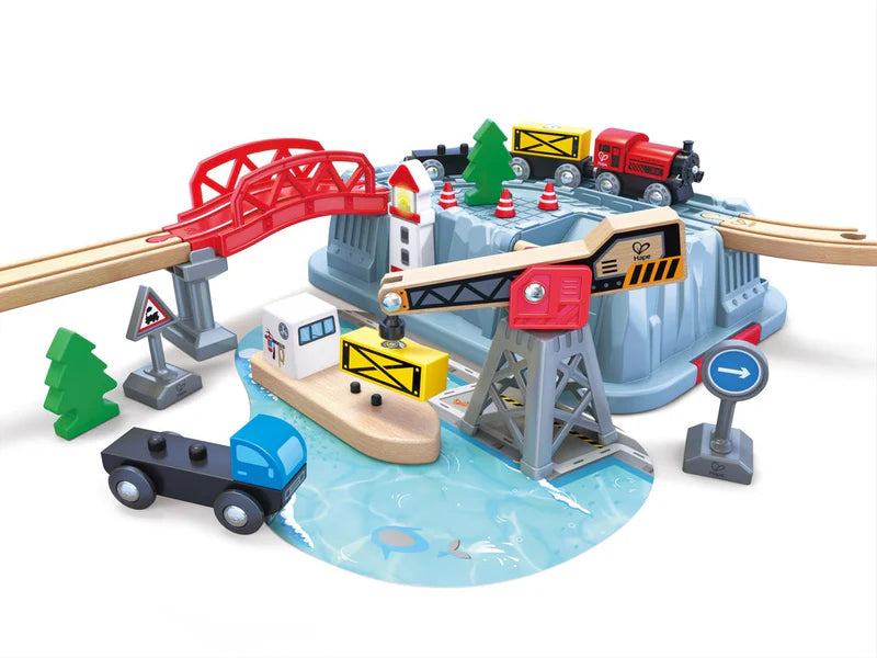 Toy train set with bridges, tracks, and vehicles on a white background