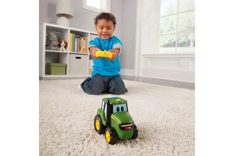 Child playing with a John Deere Johnny Tractor RC toy tractor indoors