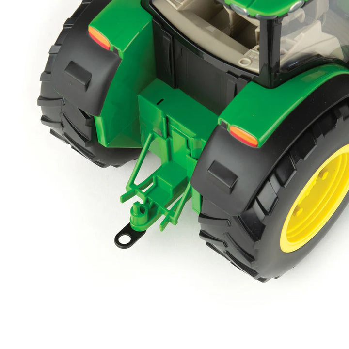 Close-up of a green toy tractor with black tires and yellow rim on a white background