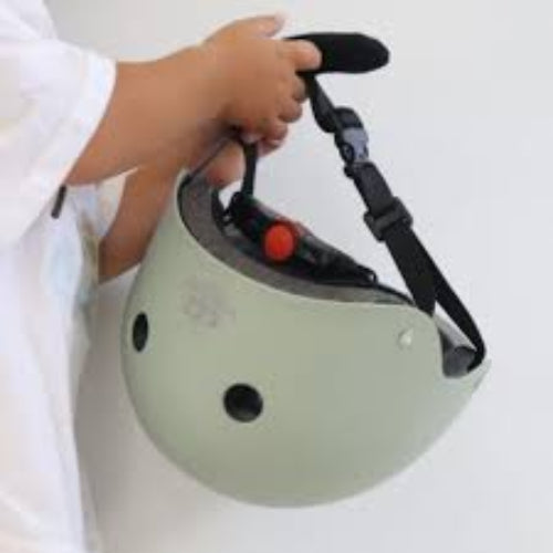 Person holding a green helmet with a black strap on a white background