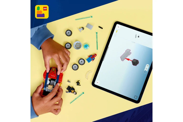 A top-down view of a person assembling a red and blue toy vehicle using small parts on a yellow surface, with a tablet showing a matching digital instruction screen. A LEGO logo appears in the top-left corner.