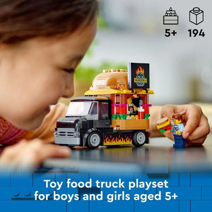 Child playing with a toy food truck playset, featuring a burger stand and hamburger figure.
