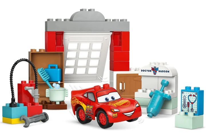 duplo set with a red lighening mcquuen car, building blocks, and medical-themed accessories on a white background
