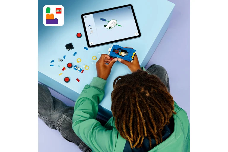 Person using a tablet with a LEGO Education app on a screen, surrounded by LEGO bricks.