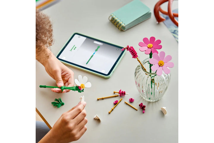Person crafting withLego Botanicals Cosmos Flowers 11514 and a tablet on a table