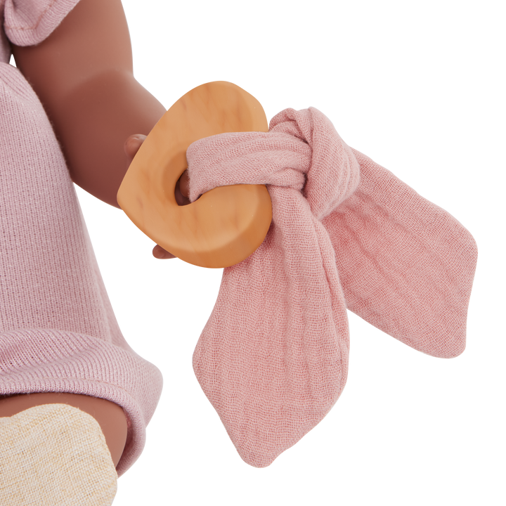 doll hand holding a wooden ring with pink textured fabric