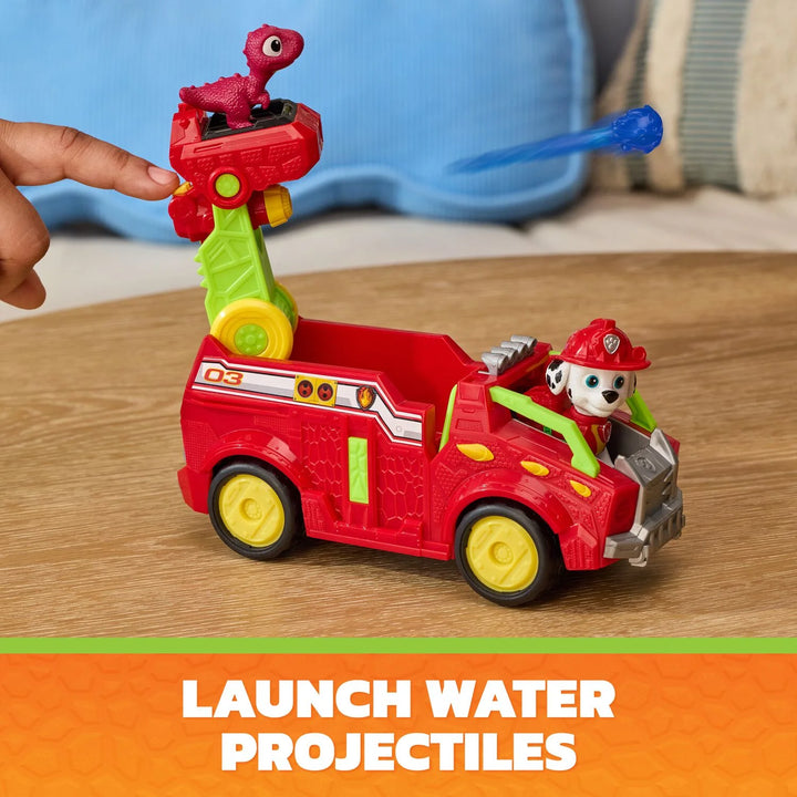 Toy paw patrol marshall fire truck with a character and dinosaur on top, on a wooden surface.