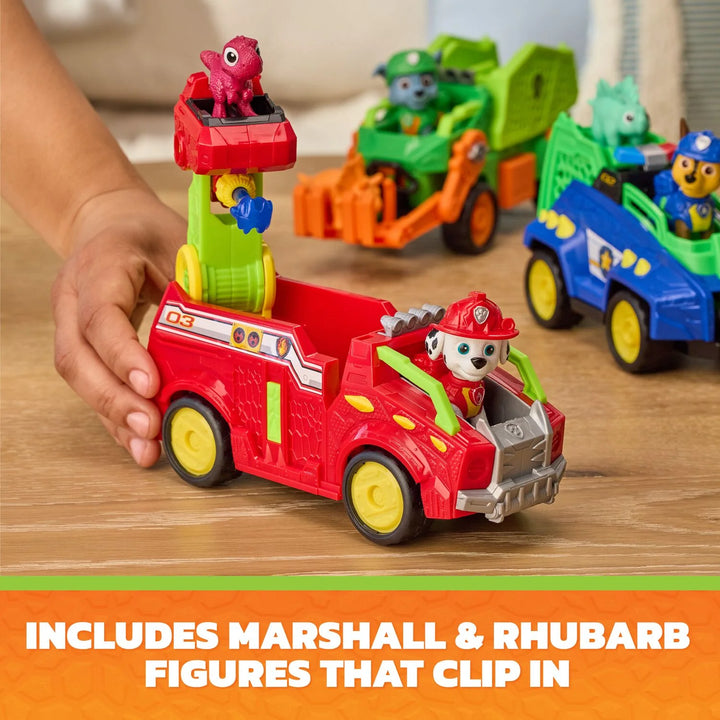 Child playing with toy vehicles including a red fire truck with figures on a wooden surface.