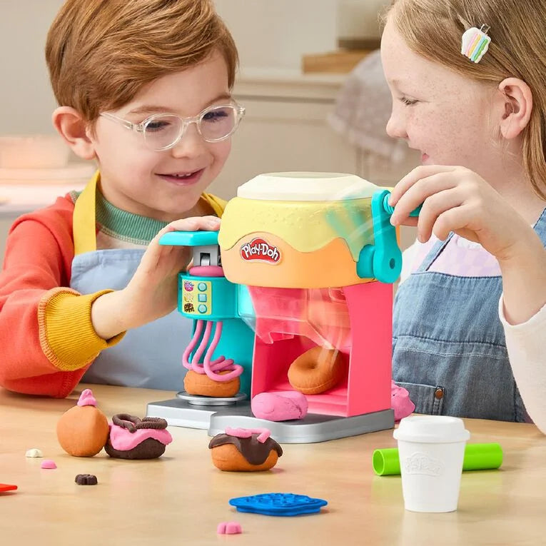 Two children playing with a toy ice cream maker set on a table.