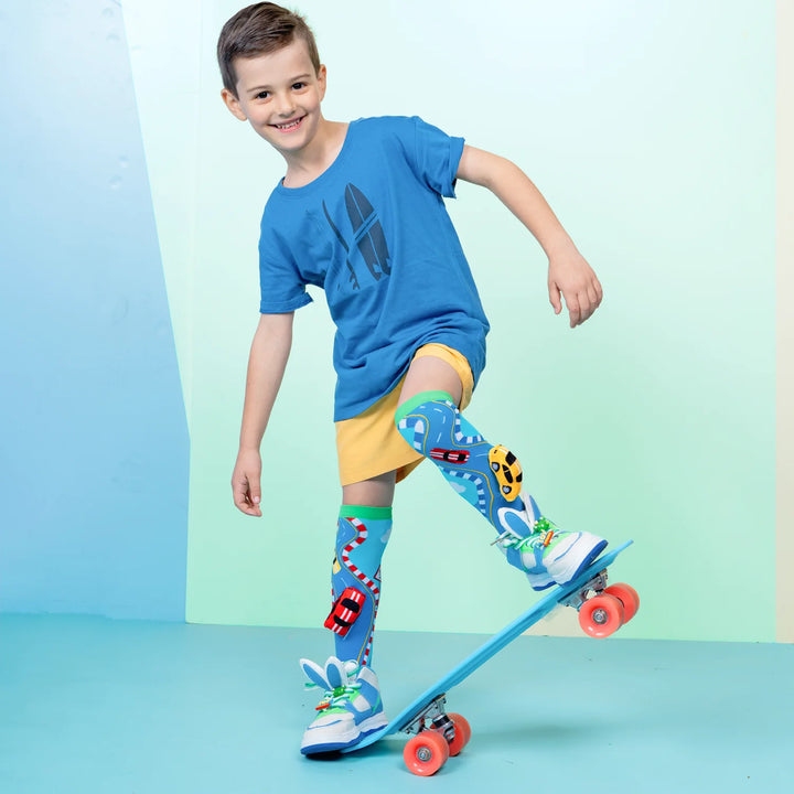 Child wearing colorful racing car socks with car design on a skateboard against a light blue background