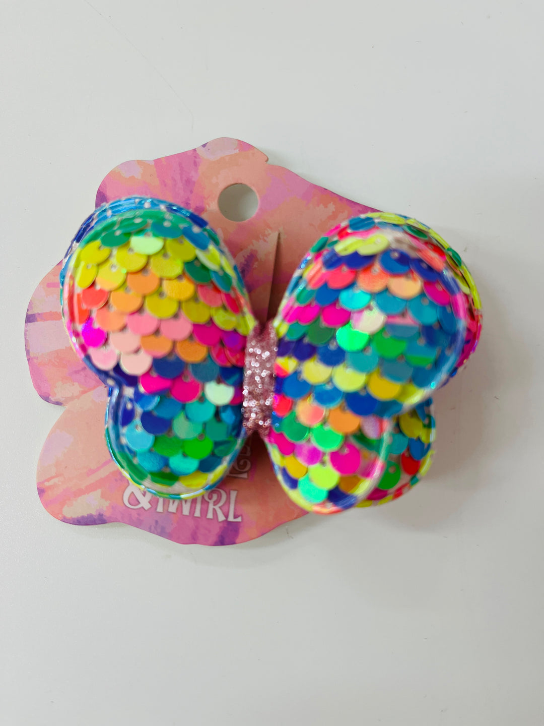 Colorful butterfly hair clip with sequins on a pink backing, brand 'Ninna Nanna' visible.