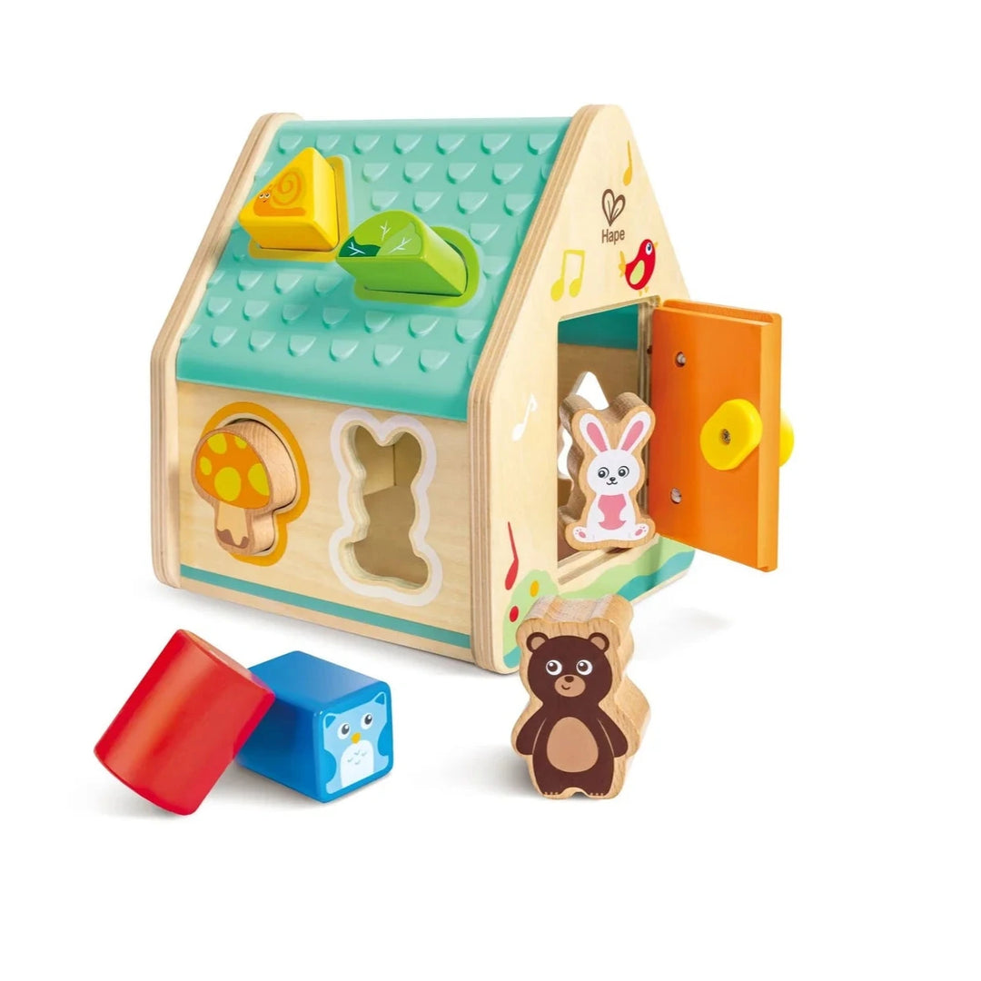 Wooden toy house with colorful shapes and animal figures on a white background
