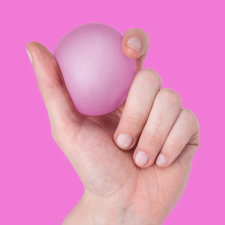 Hand holding a pink stress speks ball against a pink background