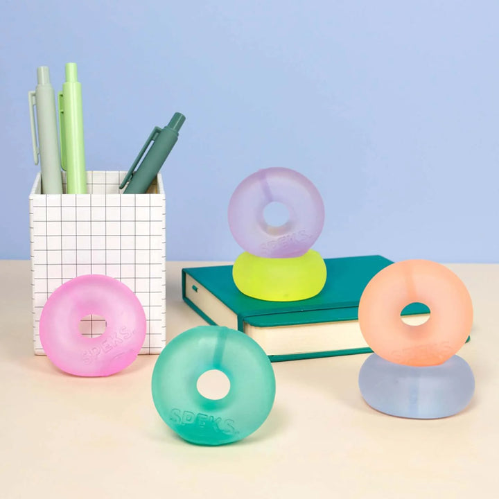 Colorful donut-shaped desk organizers on a desk with pens and books in the background.