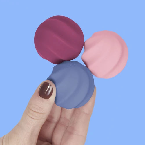 Three colorful magnetic balls held by a hand against a blue background
