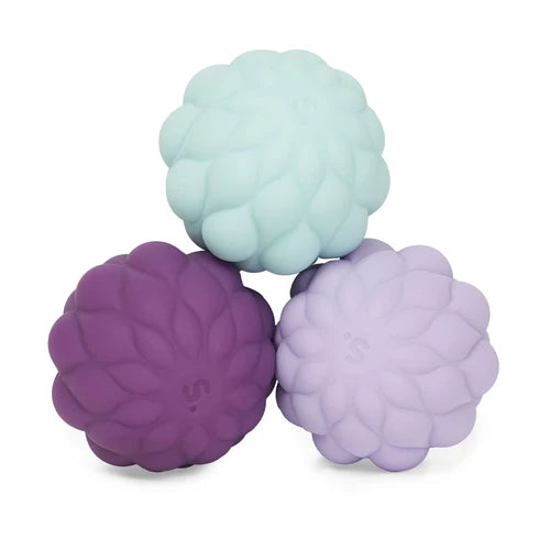 Three textured silicone balls in purple, green, and lavender on a white background