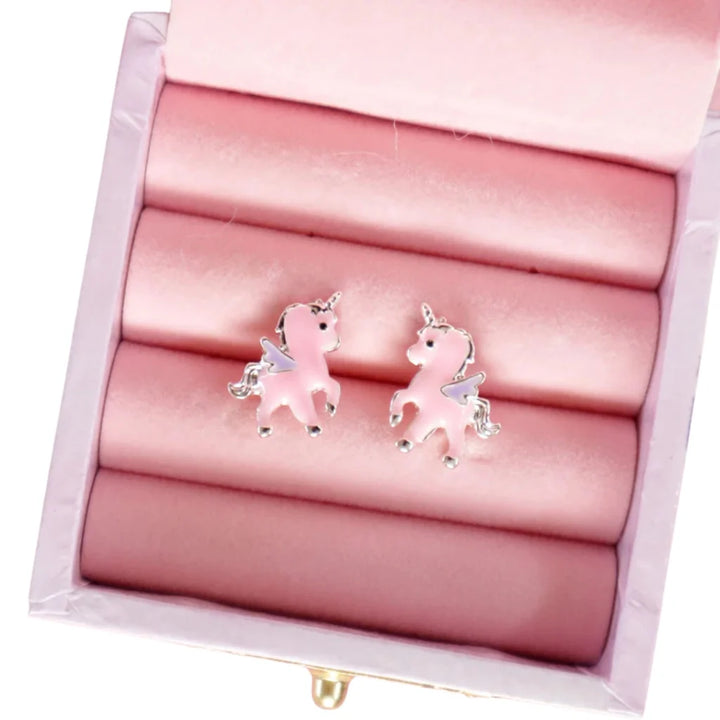 A pair of pink unicorn stud earrings with silver-toned metal outlines and wings, displayed on pink velvet ring rolls inside an open jewelry box.