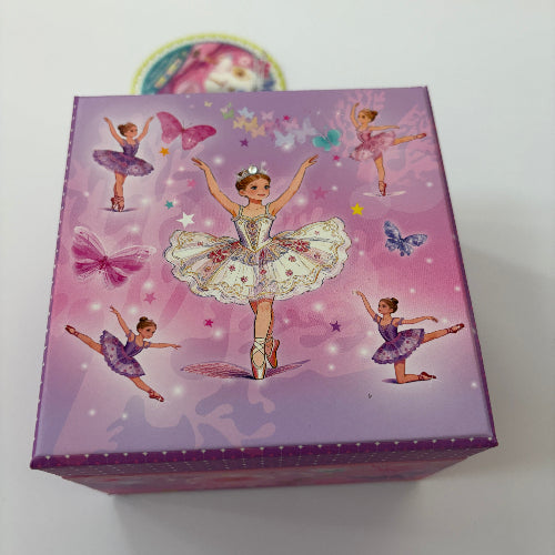 A purple and pink decorative box featuring ballerina illustrations, photographed against a plain light background.