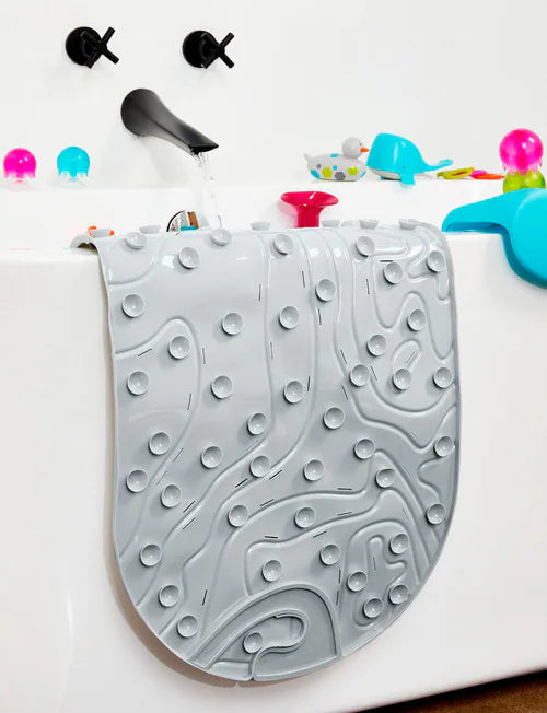 Gray textured bath mat with colorful toys on a white surface