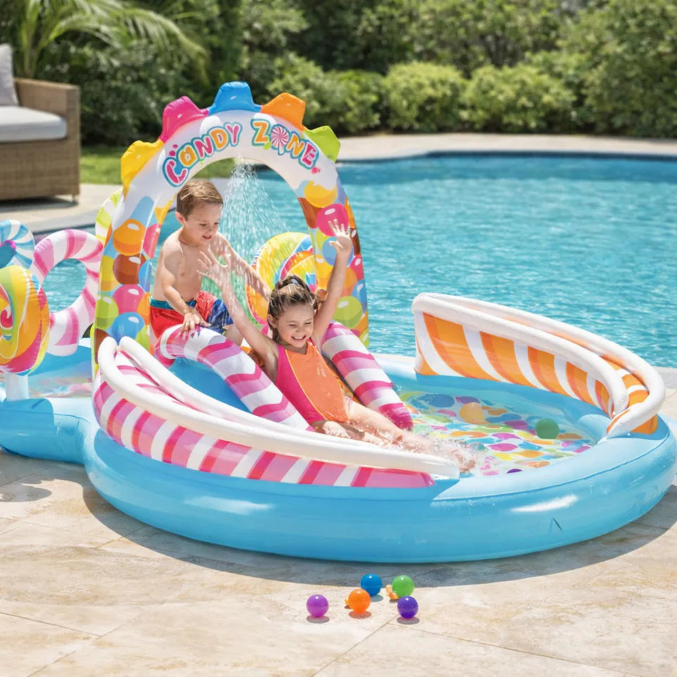 candy zone pool centre with 2 kids playing and going down slide next to pool outside