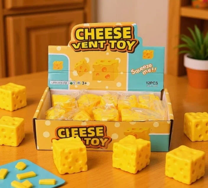 Box of Cheese Vent Toy with yellow toy cheese pieces on a wooden surface.