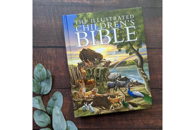 Illustrated Children's Bible on a wooden surface with decorative leaves.