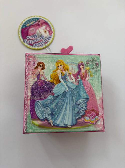 A square pink Disney-themed keepsake box featuring illustrations of princesses including Cinderella, Rapunzel, and Ariel, with a matching round sticker or tag above it on a plain white background.
