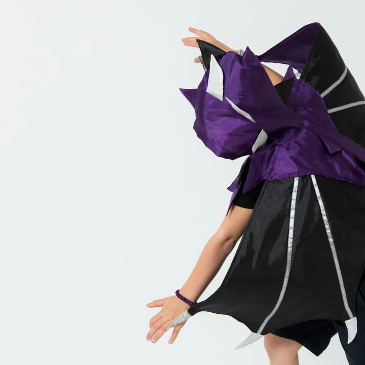 Person wearing a black and purple costume with white accents on a plain background