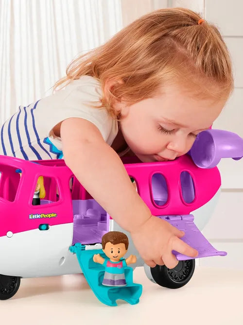 Child playing with a babrbie dream plane and figurine on a light-colored floor.