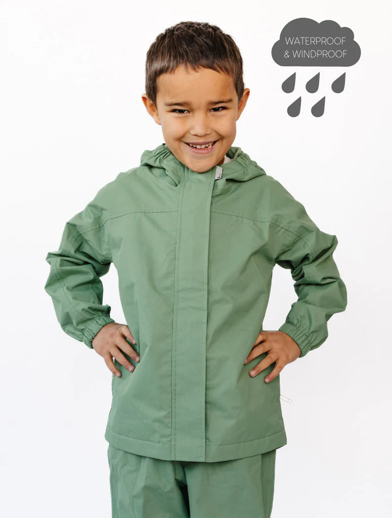 Child wearing a green waterproof jacket and pants on a white background