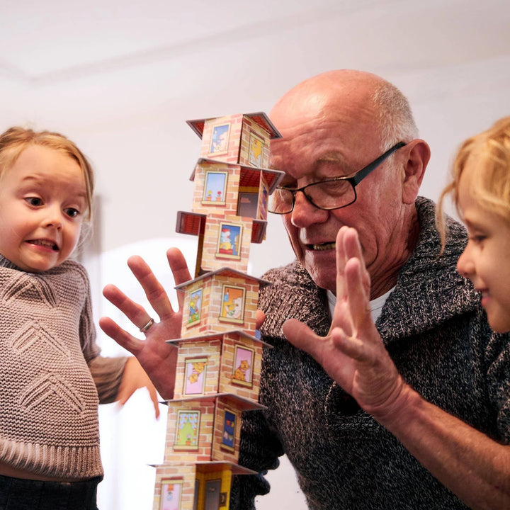 Grandfather and two children playing with a wooden house tower