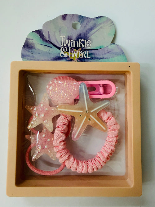 Set of hair accessories including a starfish-shaped clip, pink hair tie, and star-shaped hair tie in a 'Twinkle & Twirl' branded box.