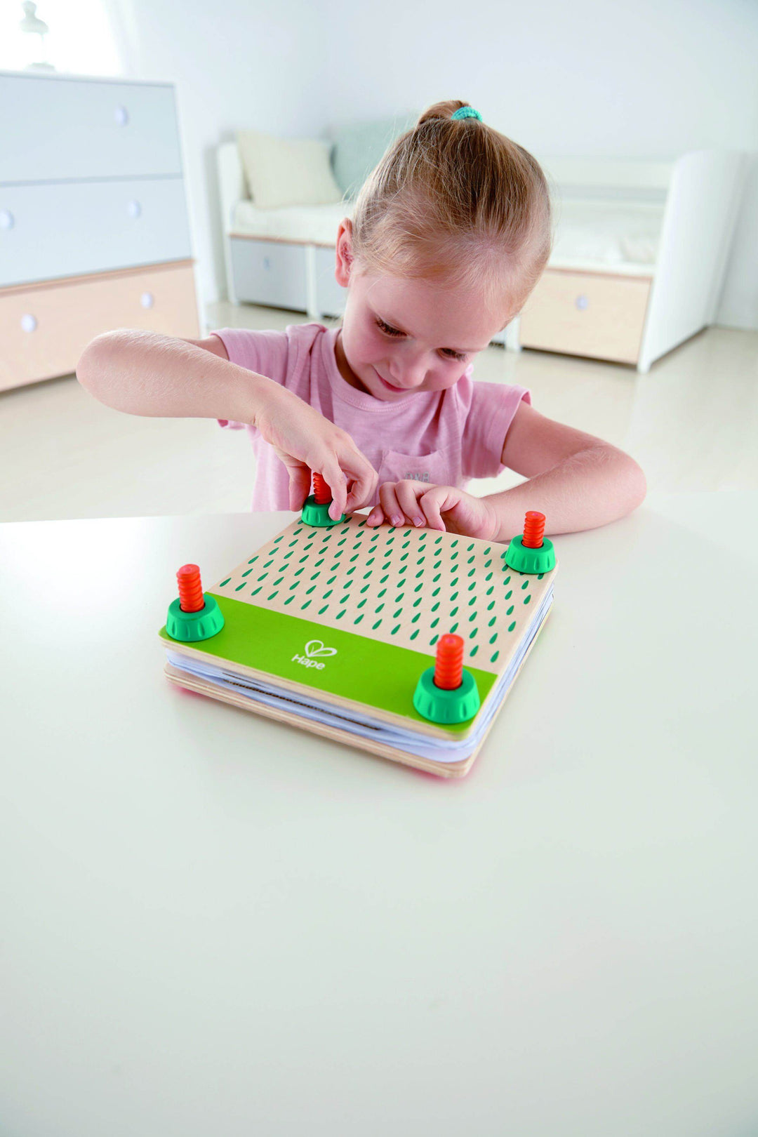 Child playing with a flower press toy on a white surface