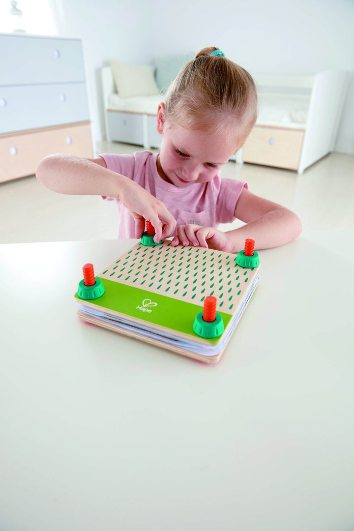 Child playing with a flower press toy on a white surface