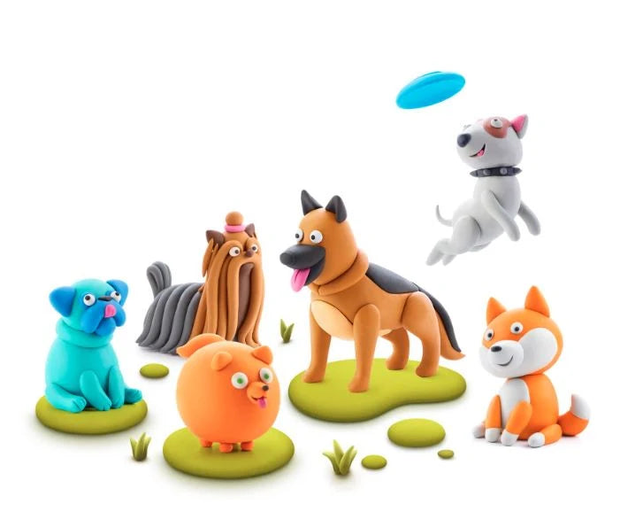 A group of colorful clay-style dog figurines posed together on a white background, including a blue pug, a gray long-haired dog, a tan German Shepherd, an orange cat-like dog, and an orange fox, with a blue frisbee floating above.