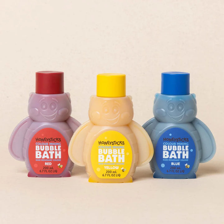 Three bottles of Honeysticks bubble bath in red, yellow, and blue on a beige background