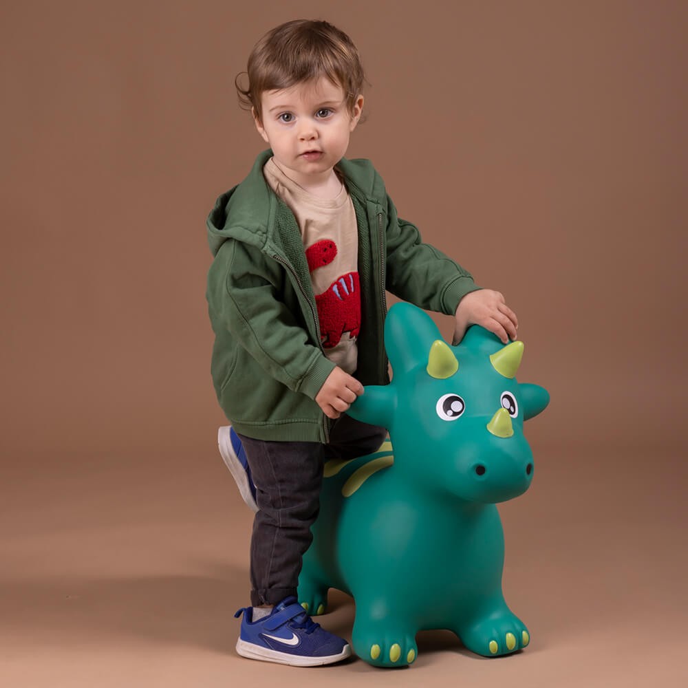 Child with a green dinosaur toy on a brown background