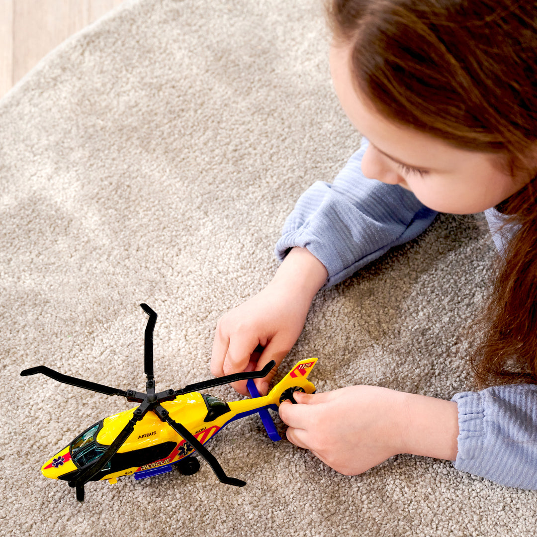 Child playing with a toy helicopter on a carpeted floor