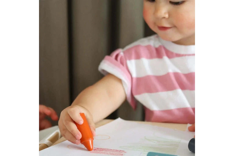 Child drawing with a red crayon on paper