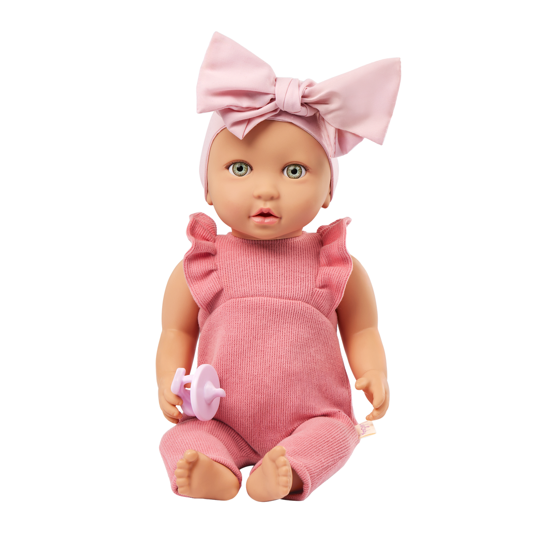 Baby doll in pink outfit with a large bow on a white background